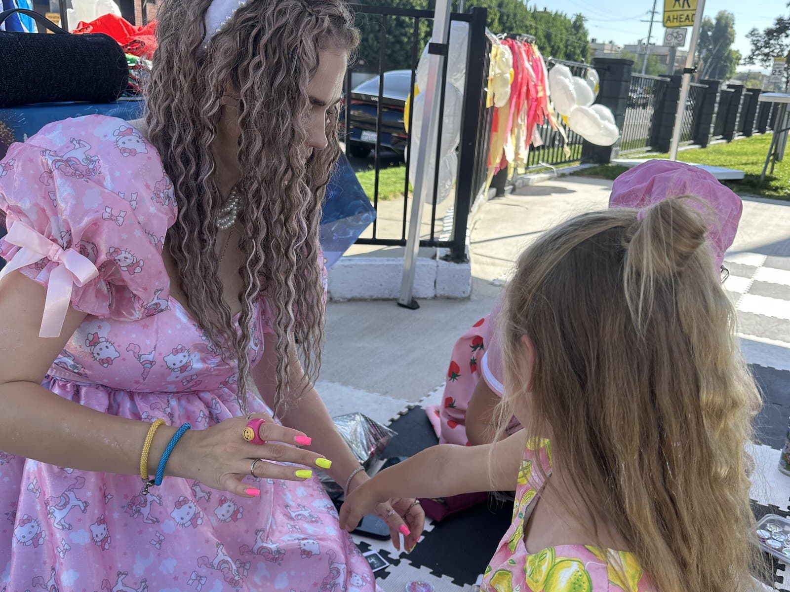 A princess-costumed performer playing with a little girl at an outdoor birthday party.